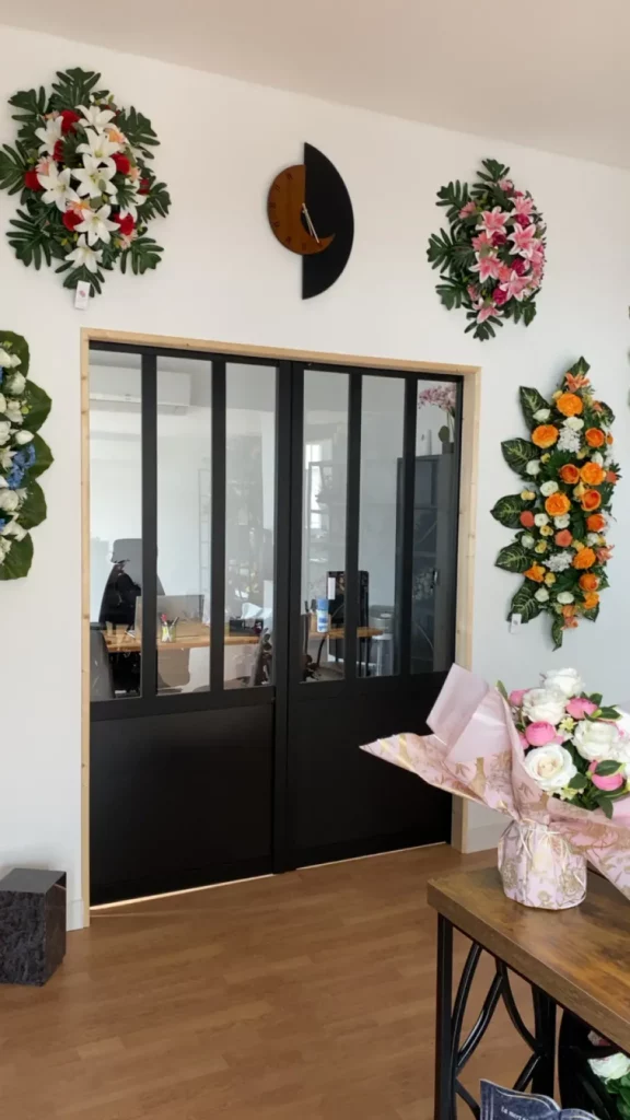 Verrière d'un magasin de pompes funèbres décorée de compositions florales.