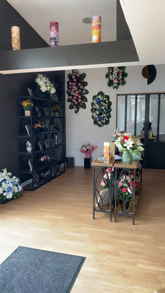 Magasin de pompes funèbres avec fleurs deuil et plaques funéraires en exposition.