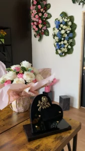 Plaque funéraire en forme de cœur et bouquet de roses dans un magasin de pompes funèbres.